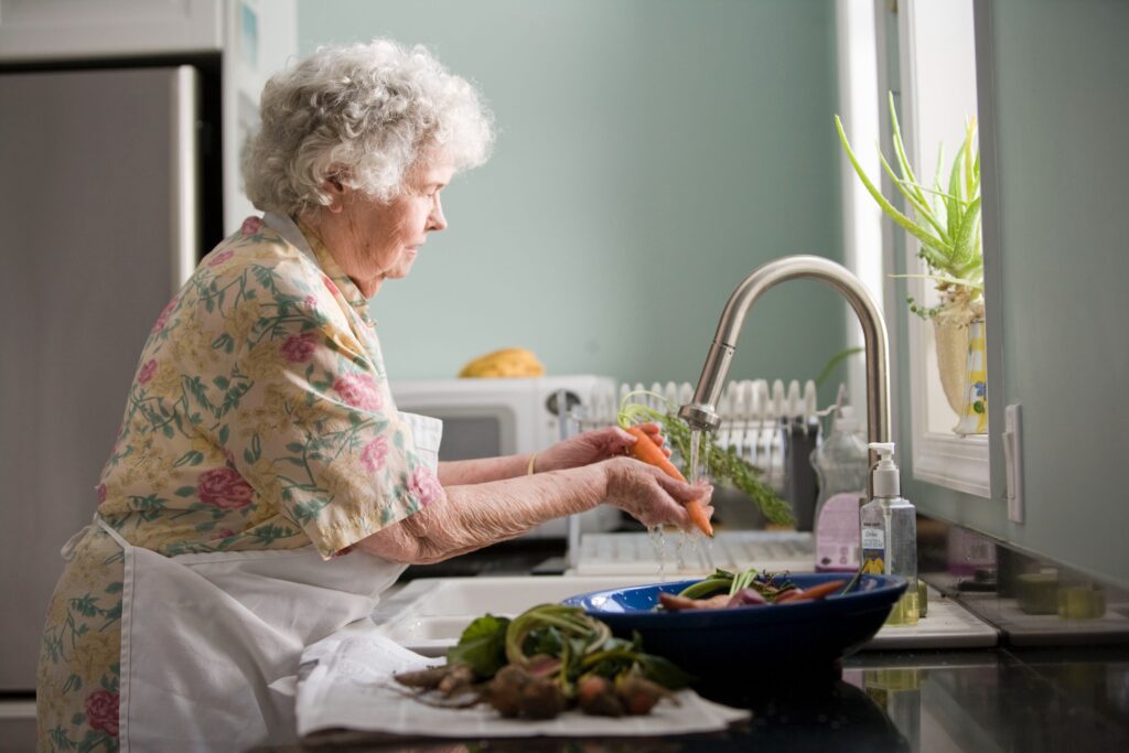 Elderly woman washing dishes- Home Modifications for Seniors blog featured image