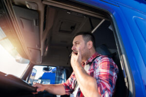 Image of a man tired at the wheel of a truck- Sleep Apnea in Trucking blog featured image