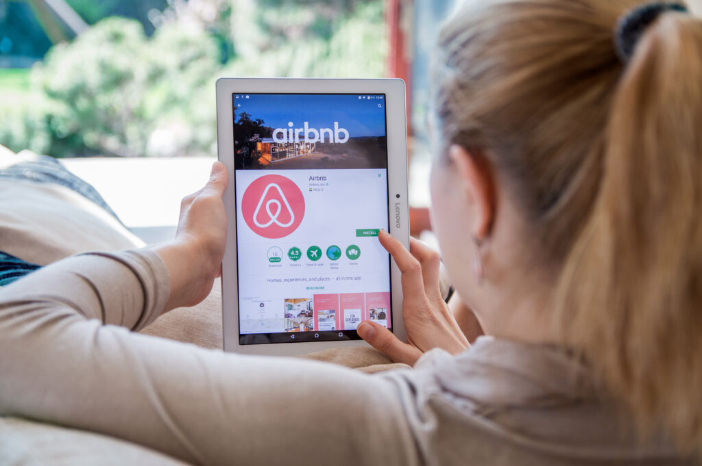 Image of a woman using Airbnb on her laptop- Airbnb Risks blog featured image