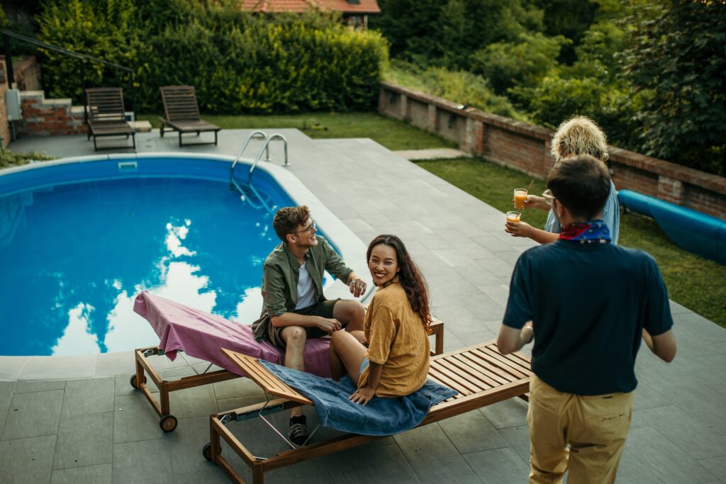 Adult friends hanging around a pool- Liability Risks blog featured image