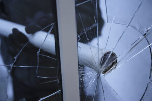 Image of someone breaking a window- Prevent Vandalism blog featured image