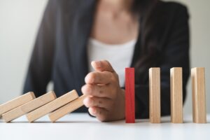 Image of a woman stopping dominoes from falling- Business Interruption blog featured image