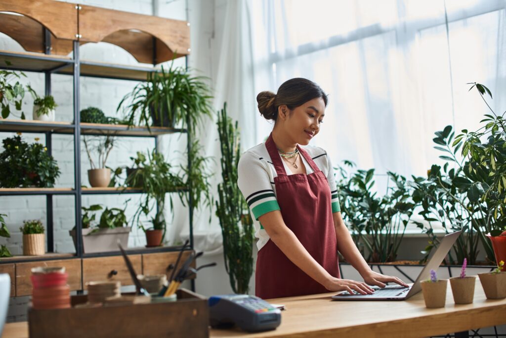 Female business owner working on a laptop at her store- Small Business Insurance Costs blog featured image