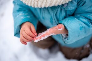 Image of a child's hands covered in snow- Frostbite Treatment & Prevention blog featured image