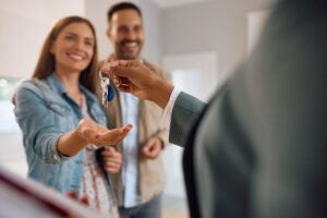 Image of a young couple getting keys to a house- Insurance-to-Value Matters blog featured image