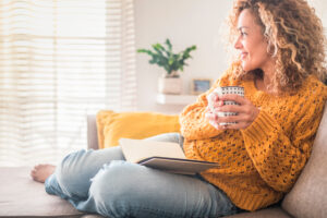 Woman sitting on couch with coffee- Insurance After Divorce blog featured image